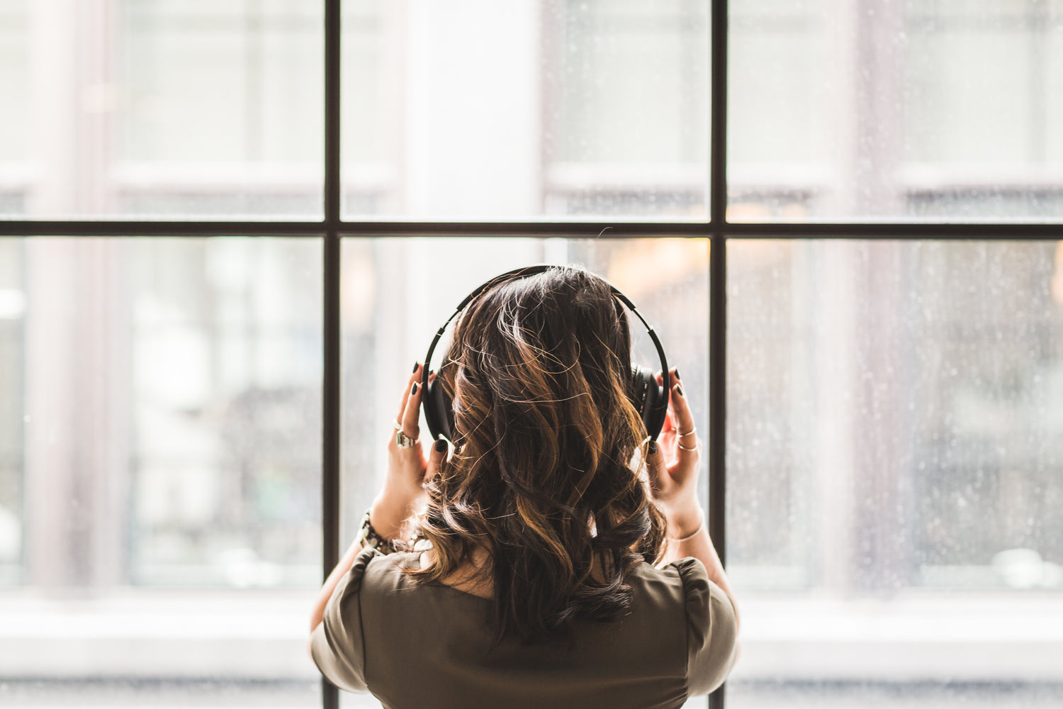 Women with headphones looks out window